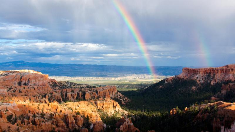 photo of two rainbows over mountains